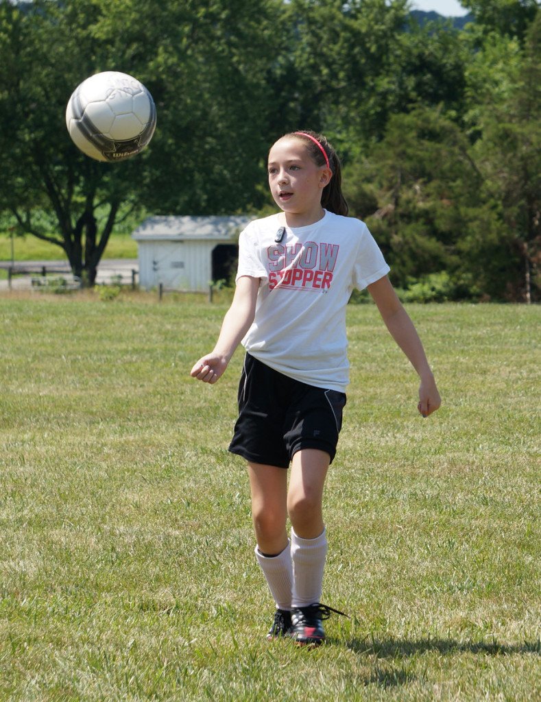 girl on soccer field with soccer ball