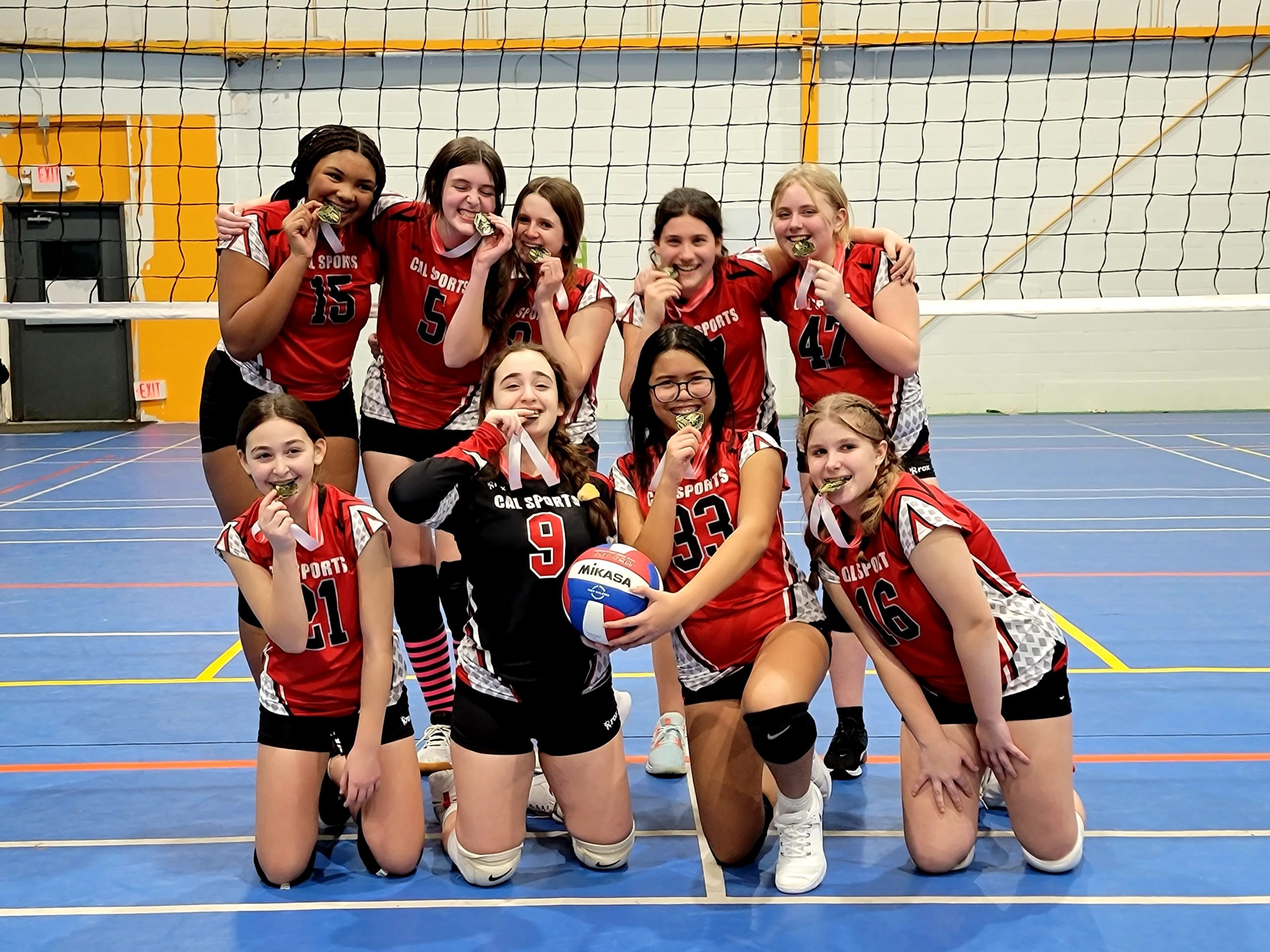 girls volleyball team on court with medals